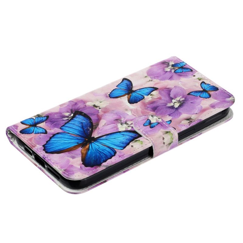 Housse iPhone 16 Papillons Bleus et Fleurs Violettes à Lanière