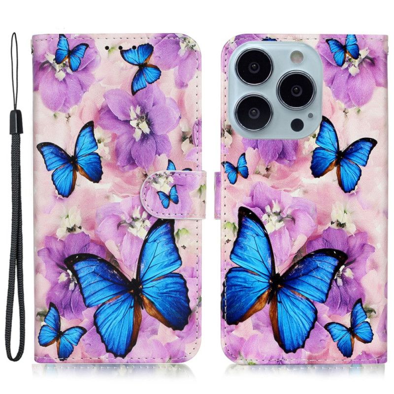 Housse iPhone 16 Pro Papillons Bleus et Fleurs Violettes à Lanière